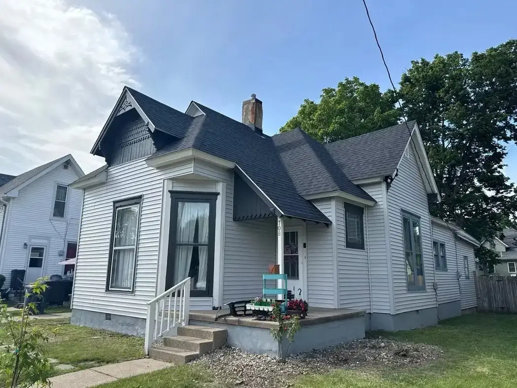 Historic home after roof and siding replacement featuring new architectural shingles, updated siding, and improved curb appeal.